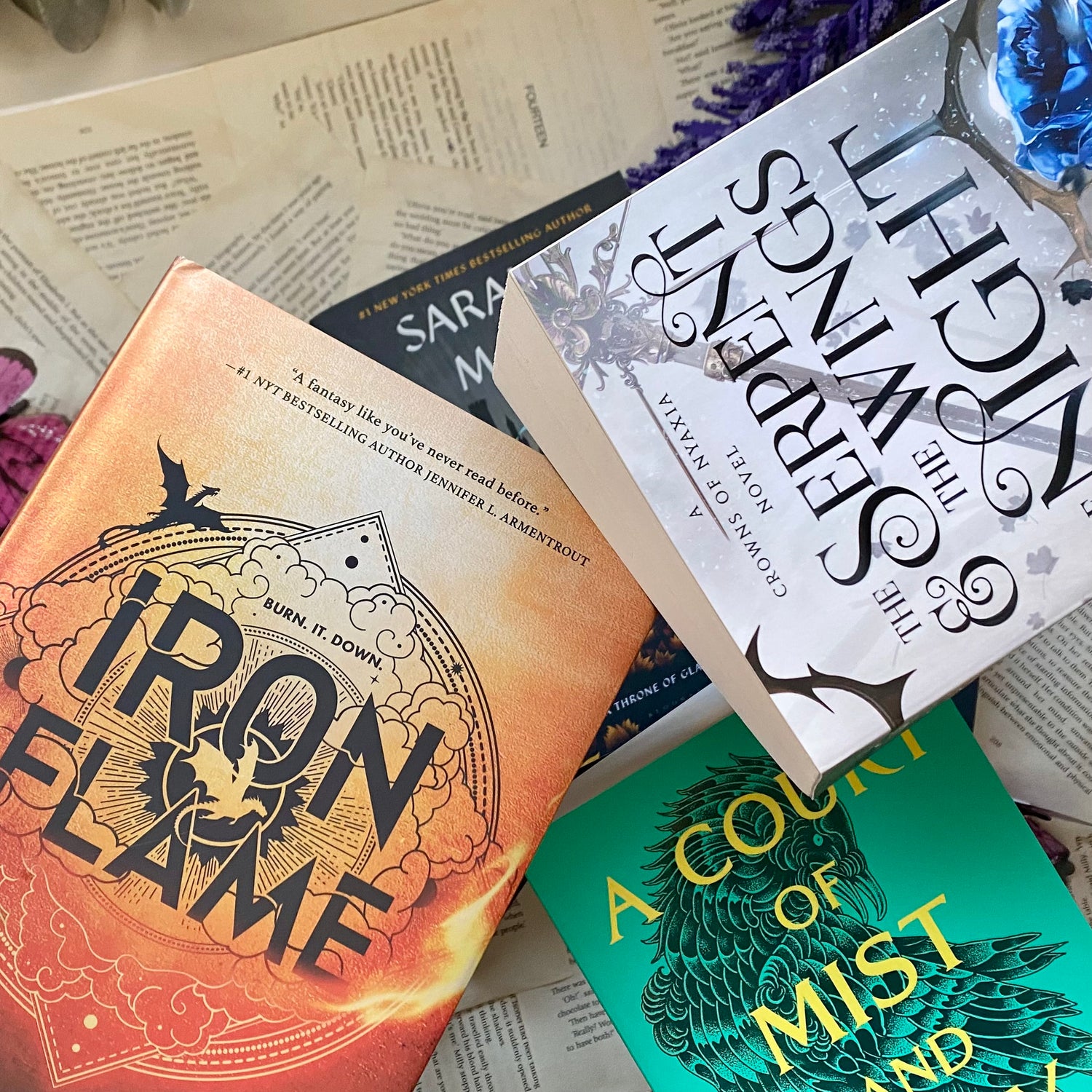 stack of fantasy romance books including Iron Flame by Rebecca Yarros,  Court of Mist and Fury by Sarah J Maas and the Serpant and the Wings of Night by Carissa broadband